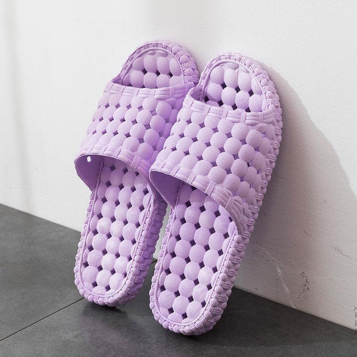 Pair of lavender purple textured bubble design slip-on indoor slippers on gray floor