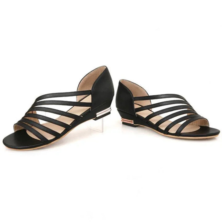 Black strappy flat sandals with low block heels and open toe design on white background