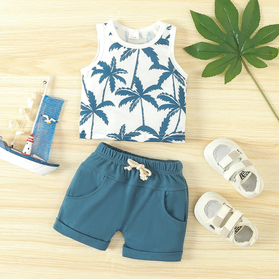 Toddler summer outfit with palm tree tank top, blue shorts, white sandals on wooden background
