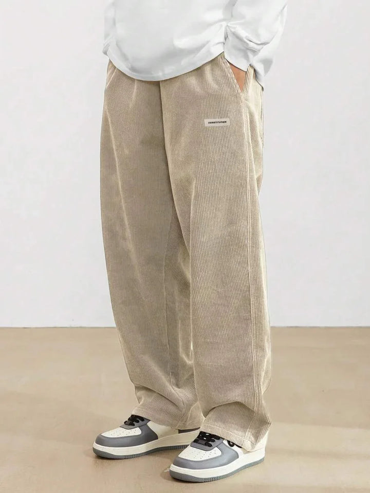 Beige corduroy wide-leg pants with pockets and white long sleeve top, paired with gray and white sneakers