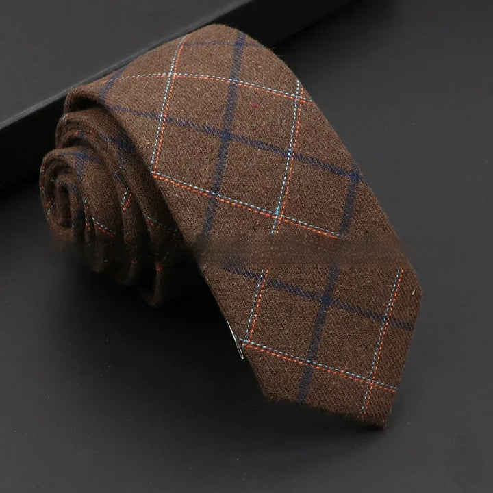 Rolled brown wool tie with navy and orange windowpane check pattern on black surface