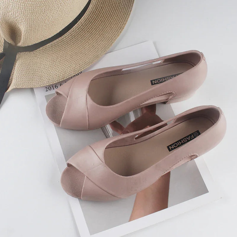 Pink open-toe women's heels on magazine with beige straw hat and black ribbon