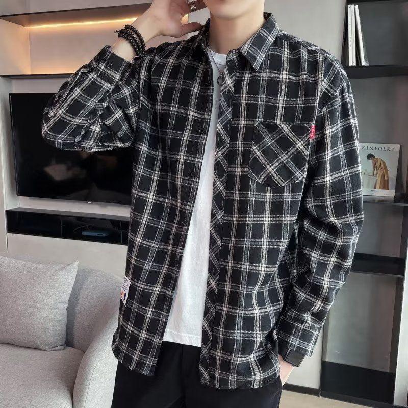 Man wearing black and white plaid flannel shirt over white t-shirt in modern living room