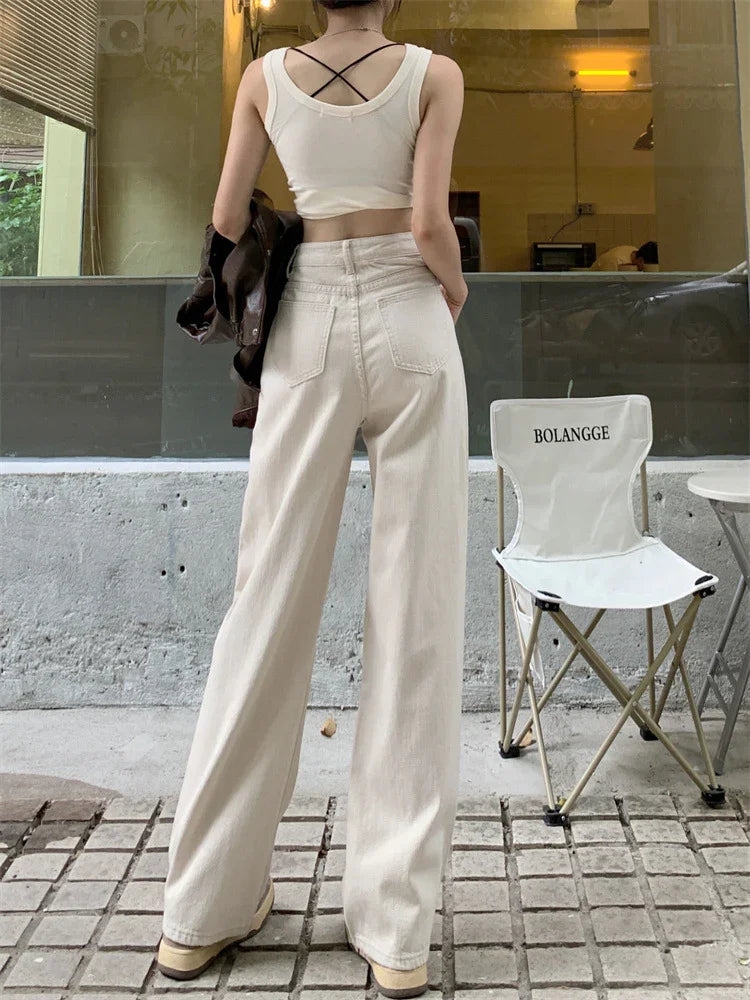 Rear view of woman wearing high-waisted beige wide-leg pants and white crop top with cross back straps