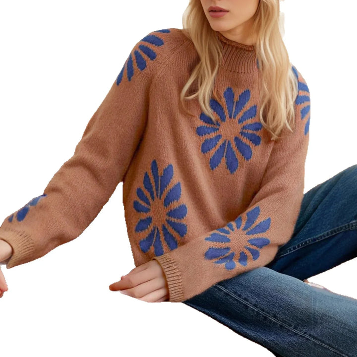 Woman wearing brown knit sweater with large blue flower patterns paired with denim jeans