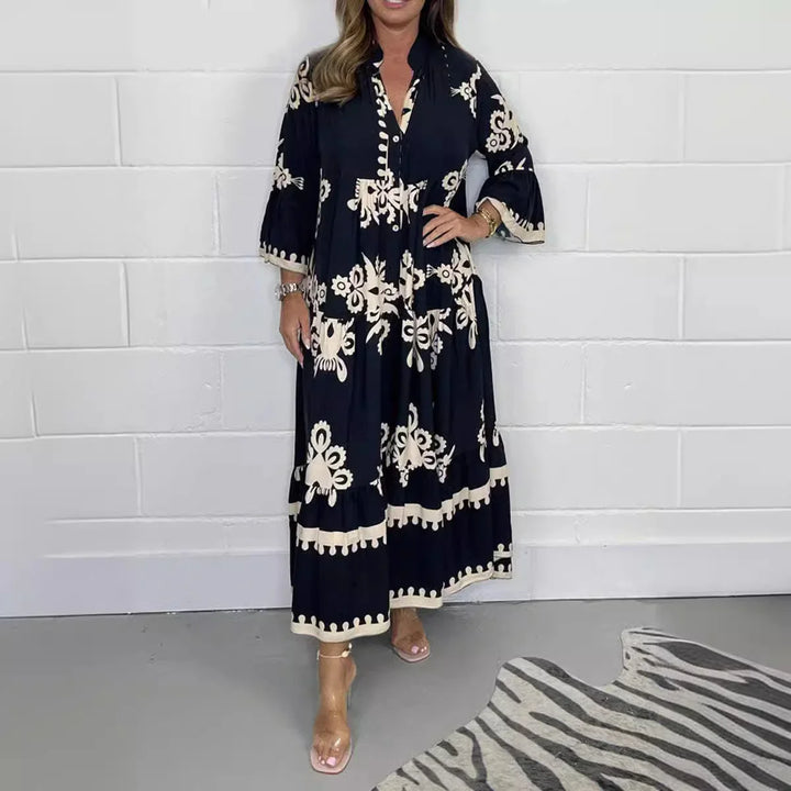 Woman wearing black and cream floral print maxi dress with three-quarter sleeves against white brick wall