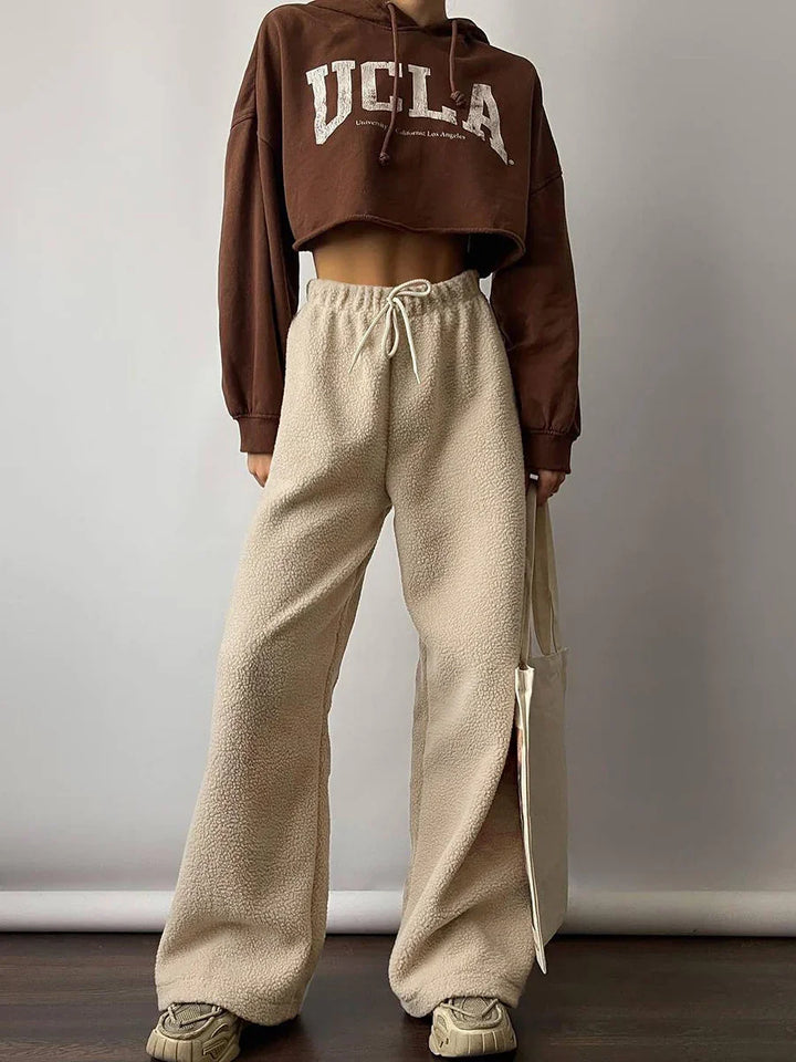 Casual outfit featuring brown cropped UCLA hoodie, beige wide-leg fleece pants, and matching sneakers
