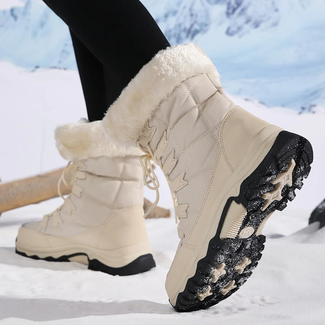 Cream winter boots with fur lining and black lug soles worn on snow