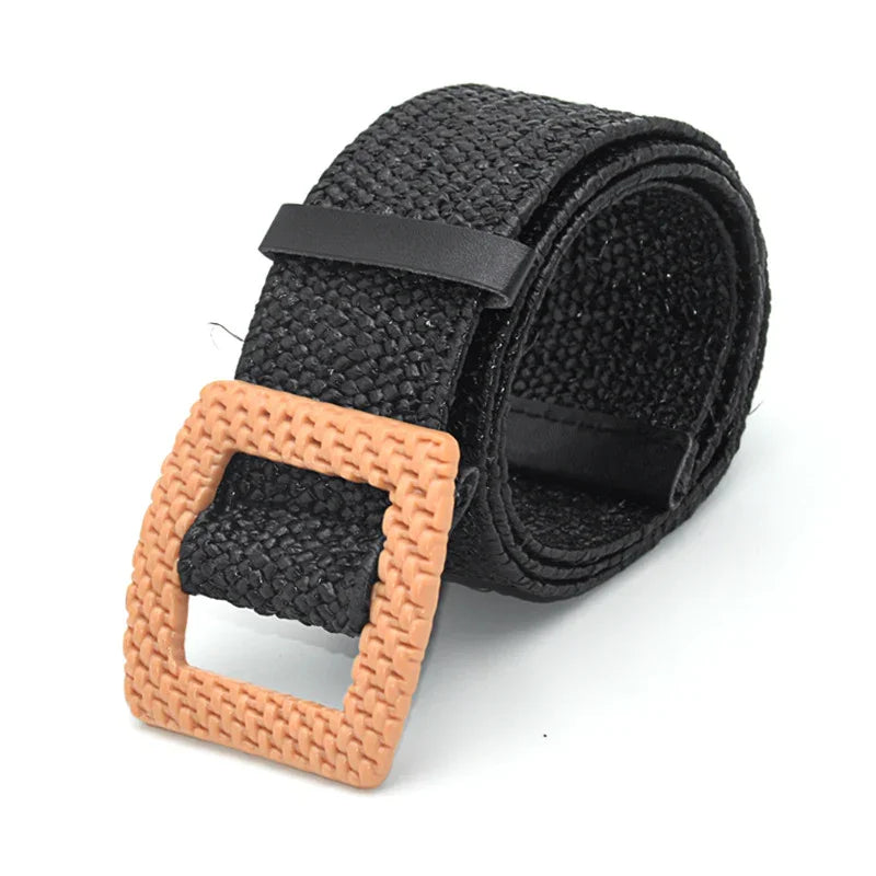 Black woven fabric belt with large textured square tan buckle on white background