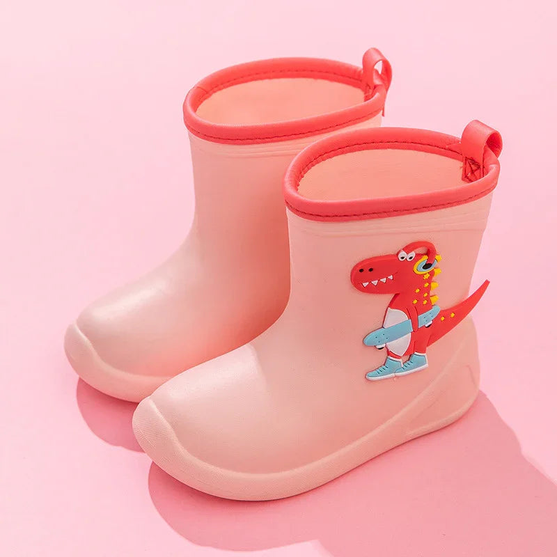 Pink children's rain boots with cartoon red dinosaur and skateboard design on a pink background
