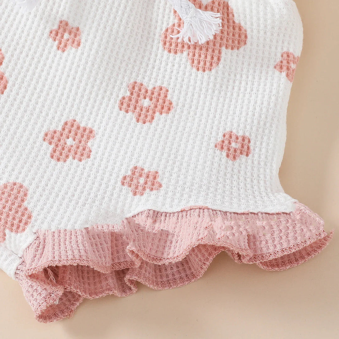 Close-up of white waffle knit fabric with pink flower prints and pink ruffled edge detail