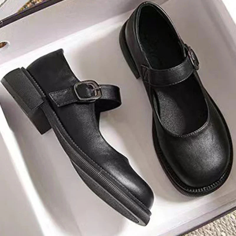 Pair of black leather Mary Jane shoes with buckle straps in a white box