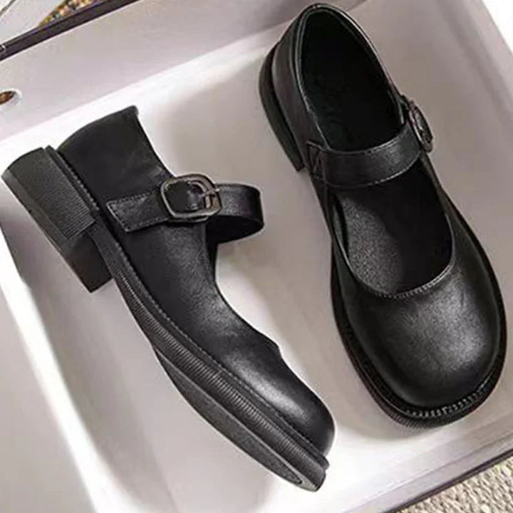 Pair of black leather Mary Jane shoes with buckle straps in a white box