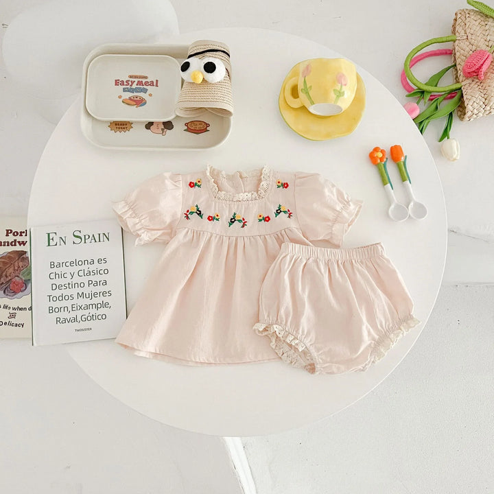 Baby girl pale pink dress with flower embroidery and matching shorts on white table