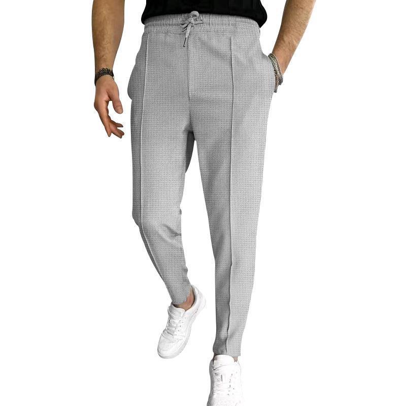 Men's light gray textured jogger pants with drawstring waist and side pockets, paired with white sneakers