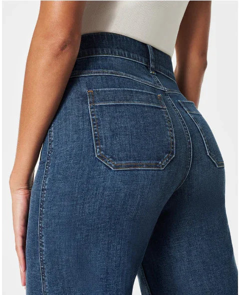 Close-up of woman wearing high-waisted dark blue denim jeans with back pockets and white top