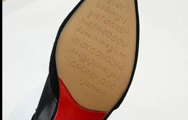 Close-up of black formal shoe sole with red accent and embossed text pattern