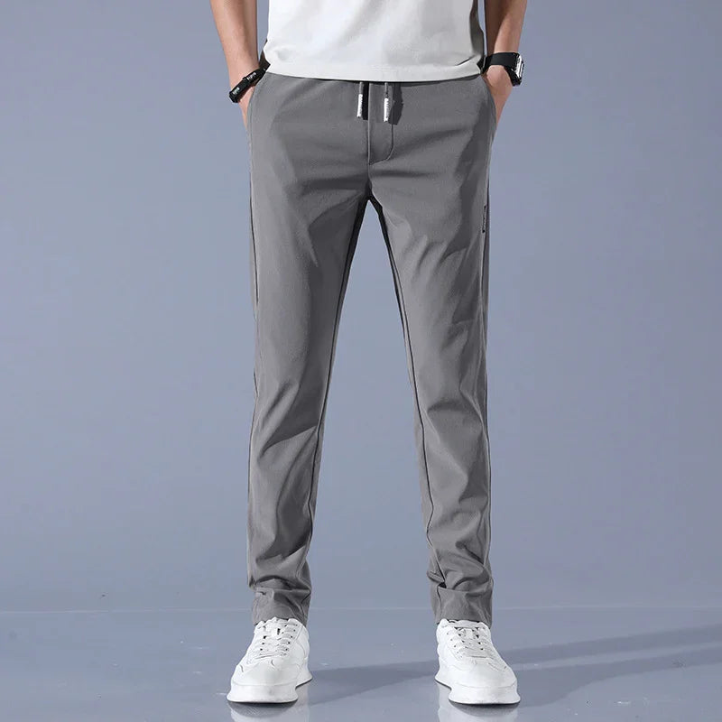 man wearing gray casual pants with drawstring and white sneakers on gray background