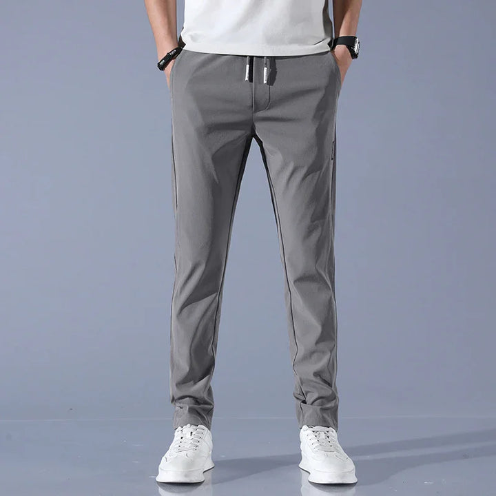 man wearing gray casual pants with drawstring and white sneakers on gray background