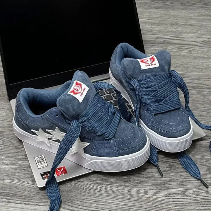 Blue suede sneakers with white star accents and thick laces on a laptop keyboard