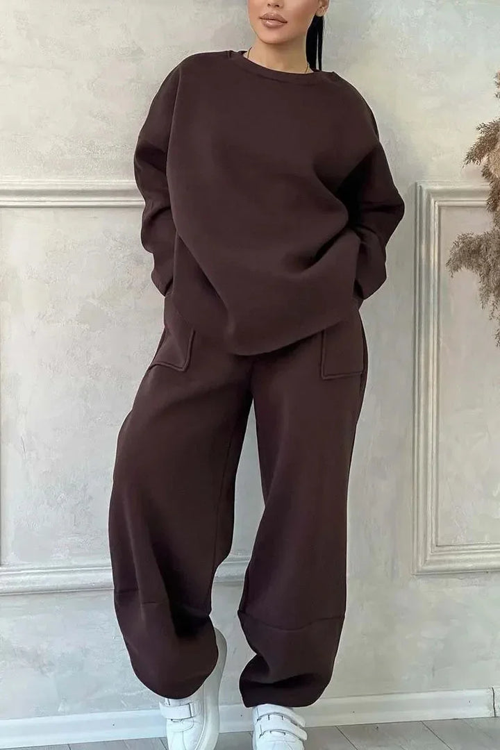 Woman wearing dark brown oversized sweatshirt and matching jogger pants with white sneakers indoors