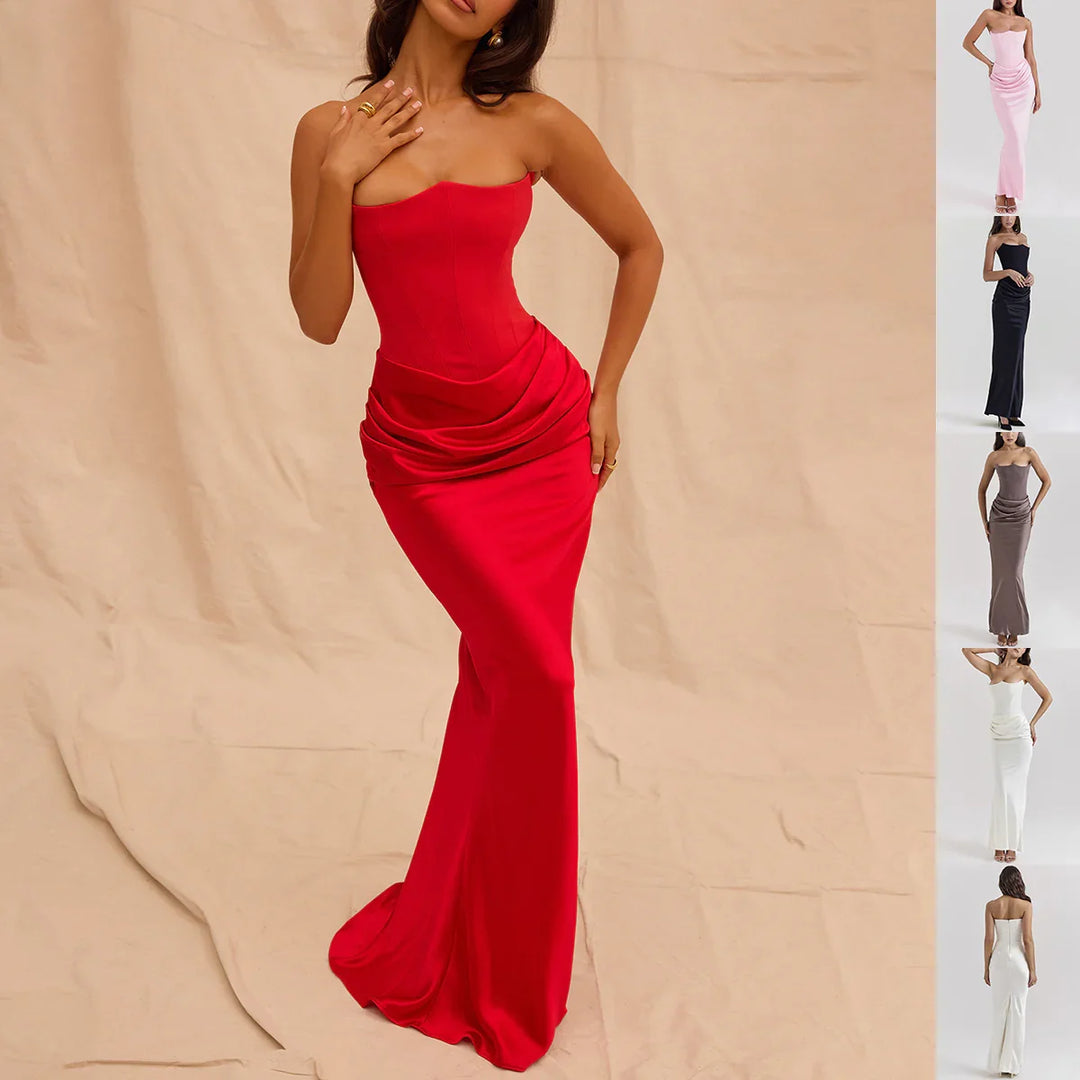 Woman wearing a strapless red evening gown with draped waist detail against beige backdrop