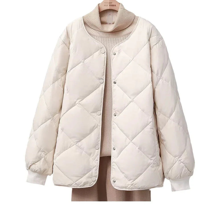 Beige quilted puffer jacket with snap buttons on a turtleneck sweater background