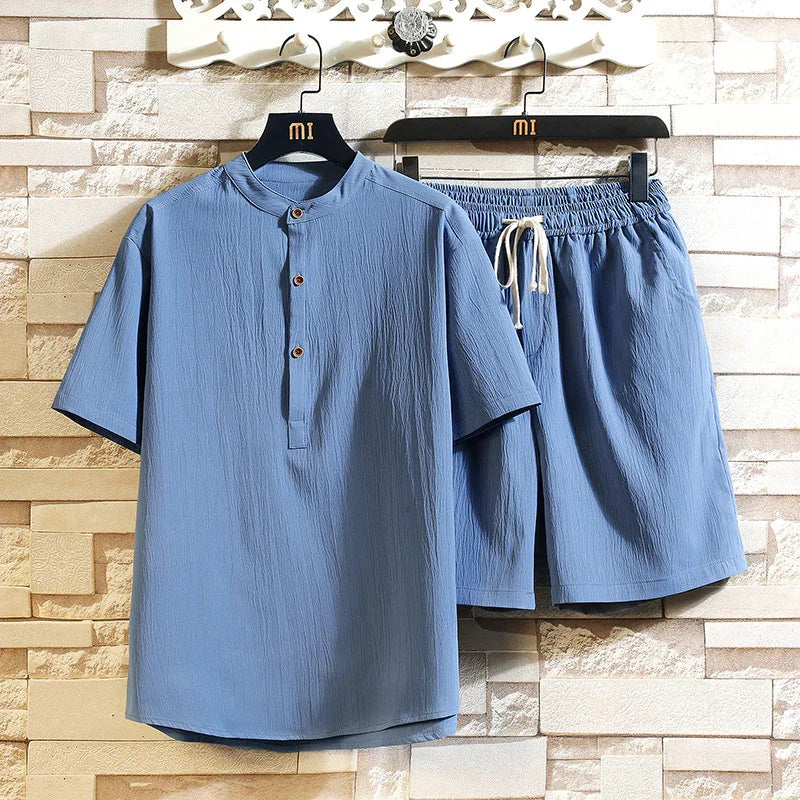 Light blue short sleeve mandarin collar shirt and matching elastic waist shorts set on hangers against stone wall