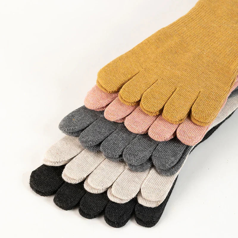 Stack of colorful knit toe socks in mustard, pink, gray, cream, and black on white background