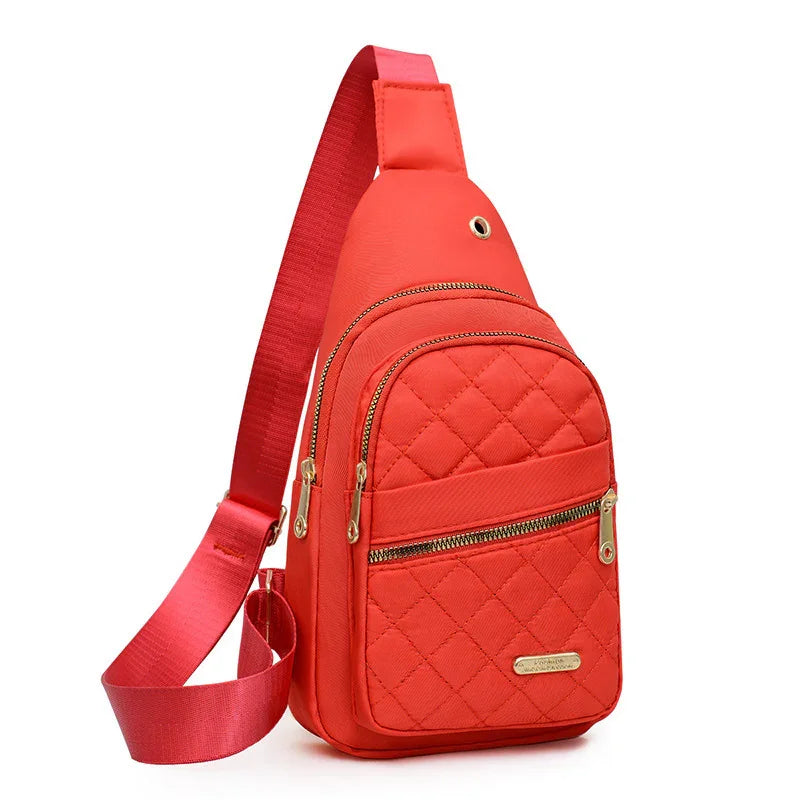 Red quilted crossbody sling bag with gold zippers and adjustable strap on white background