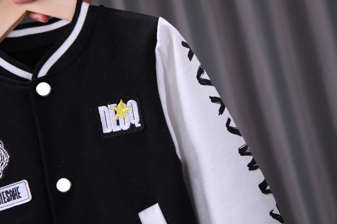 Black and white varsity jacket with yellow star patch and white lettering on sleeve