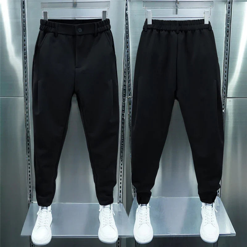 Front and back view of black jogger pants with elastic waist and cuffs, paired with white sneakers