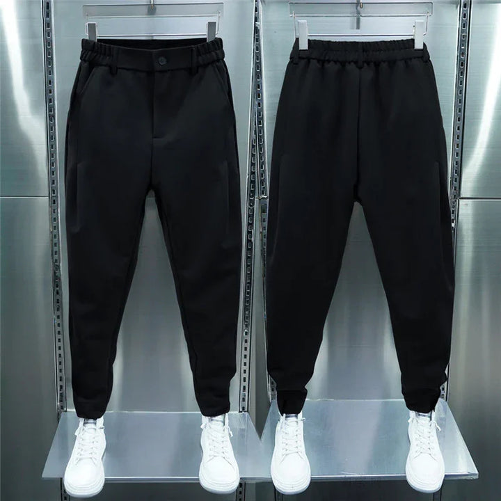 Front and back view of black jogger pants with elastic waist and cuffs, paired with white sneakers