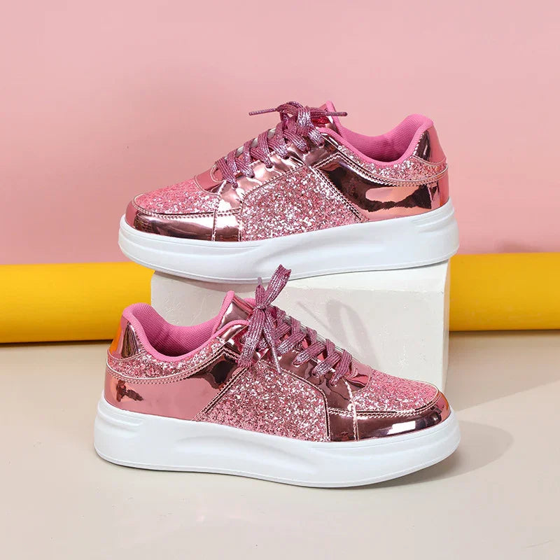 Pink glittery women's platform sneakers with shiny metallic panels and white soles on a white block