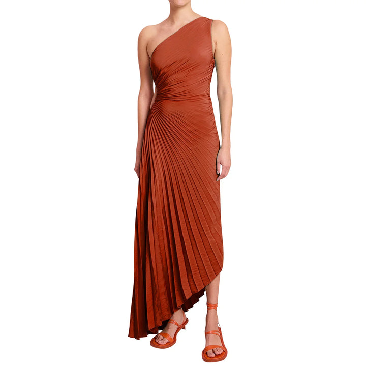 Woman wearing an asymmetrical rust orange pleated dress with matching strappy sandals
