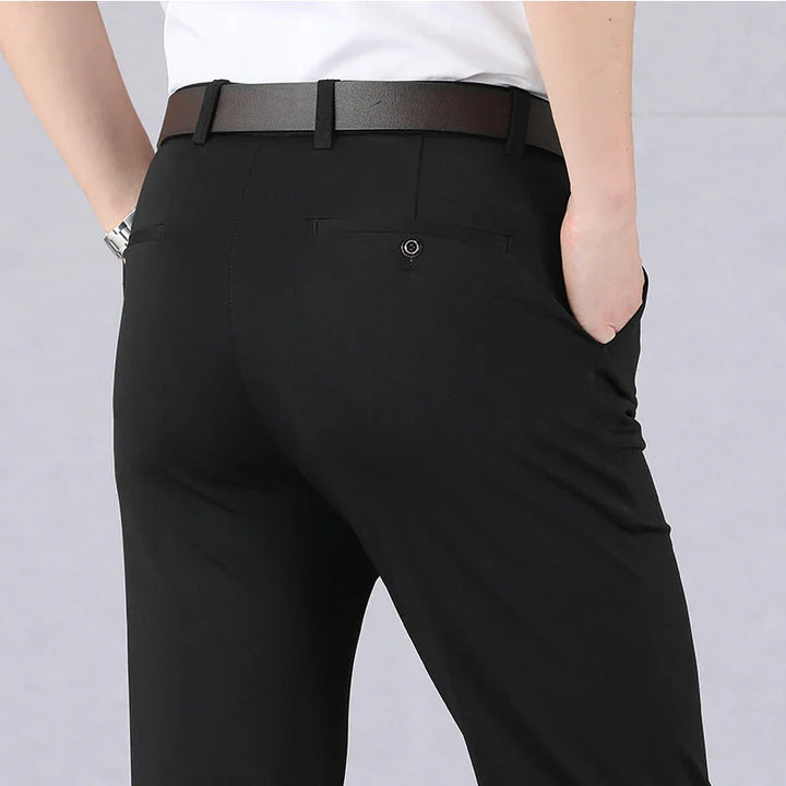 Back view of person wearing black formal trousers with belt and white shirt, hands in pockets