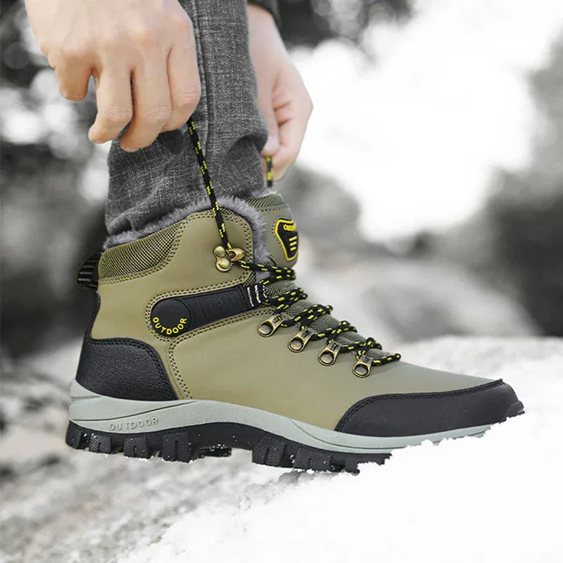 Close-up of person tying green and black outdoor hiking boot on snowy ground