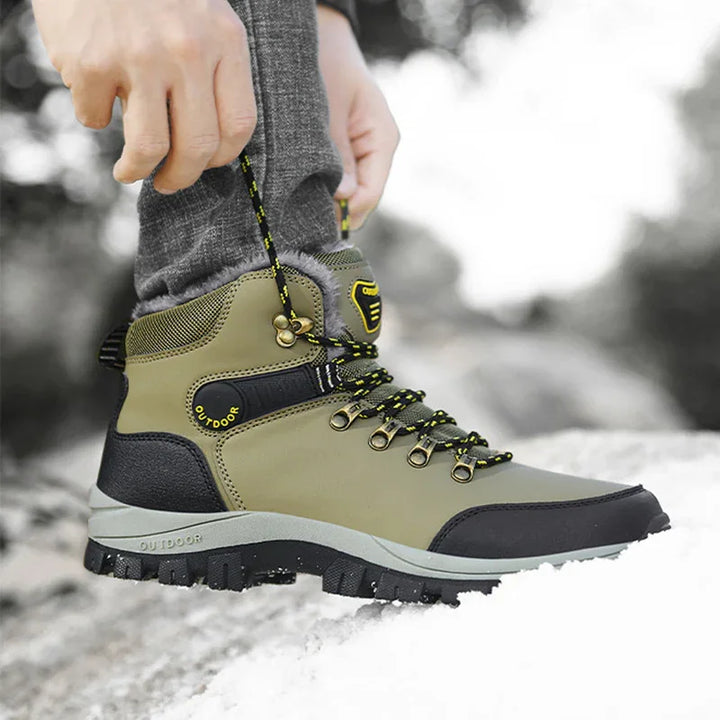 Close-up of person tying green and black outdoor hiking boot on snowy ground