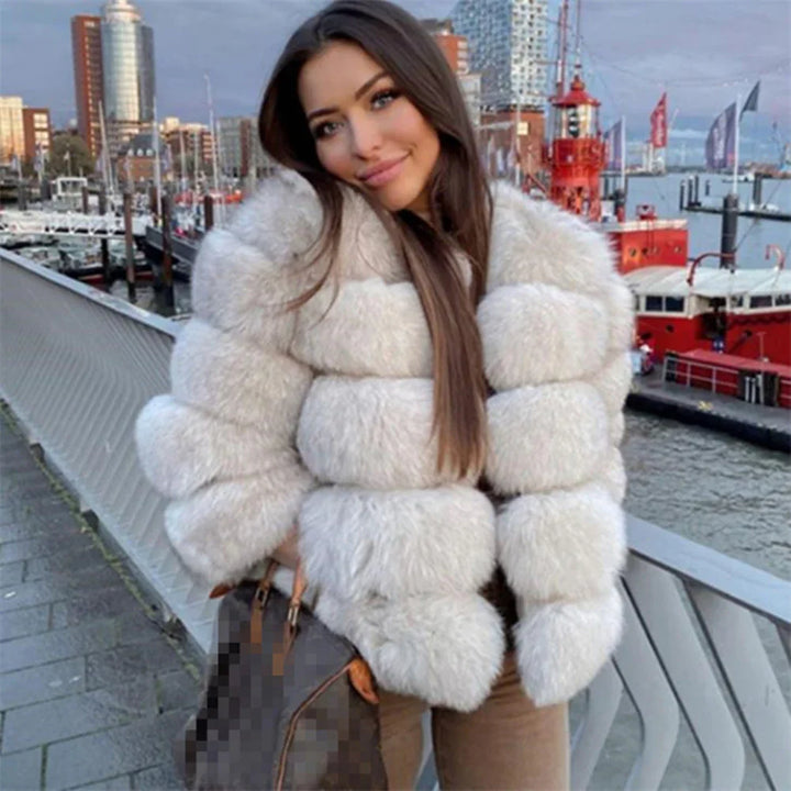 Woman in white fluffy fur coat holding designer bag on city waterfront bridge with red ships