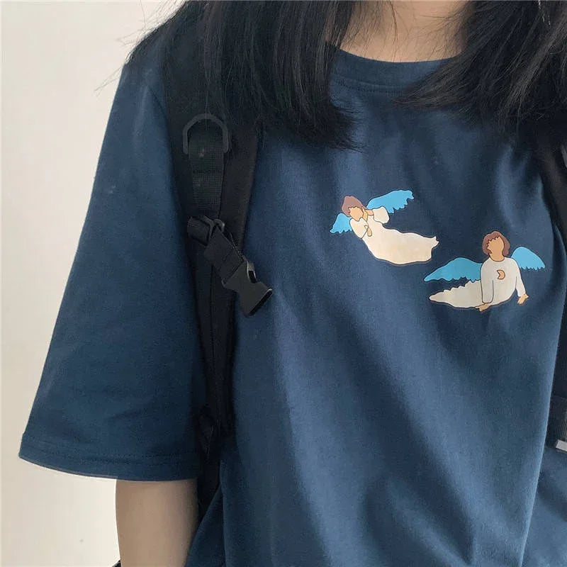 Close-up of person wearing navy blue t-shirt with two cartoon angels and a black backpack strap