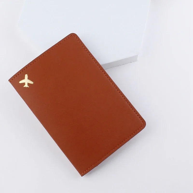 Brown leather passport holder with gold airplane icon on white background