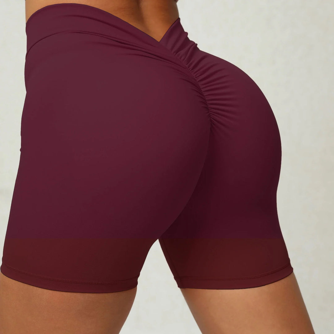 Close-up of a woman wearing burgundy high-waist ruched booty shorts in sportswear