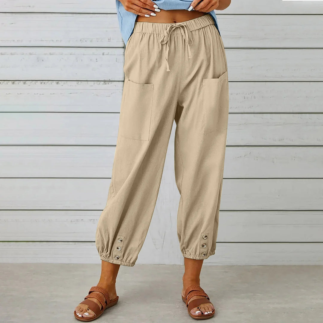 Woman wearing beige casual drawstring pants with front pockets and button details near ankles