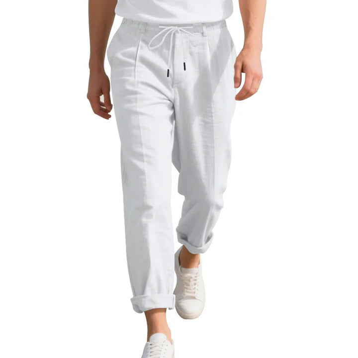 Man wearing white casual jogger pants with rolled cuffs and white sneakers walking