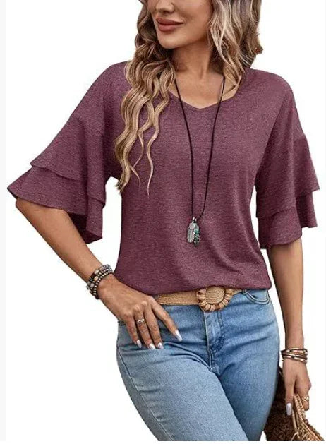 Woman wearing a purple ruffle sleeve top paired with light blue jeans and boho accessories