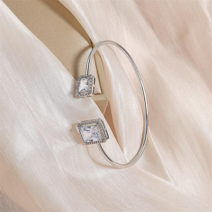 elegant silver bangle bracelet with two large square clear crystals on light beige satin fabric