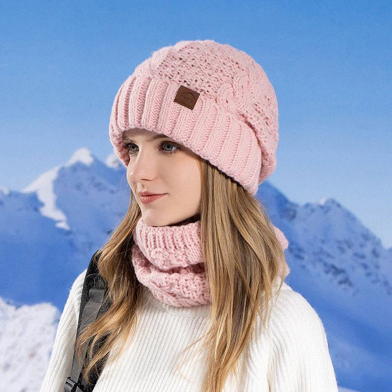Woman wearing pink knit hat and matching scarf with snowy mountain background