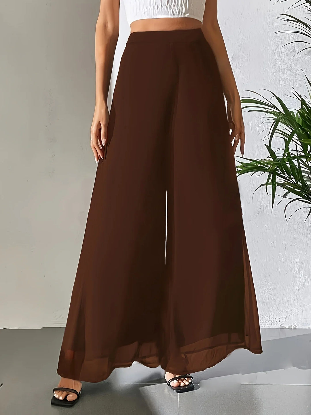 Woman wearing brown wide-leg pants paired with a white crop top and black sandals indoors