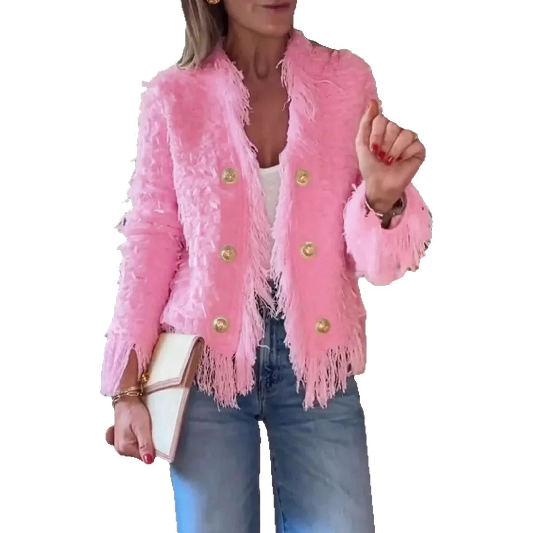 Woman wearing a pink fringed double-breasted jacket with gold buttons, white top, blue jeans, and holding a white clutch