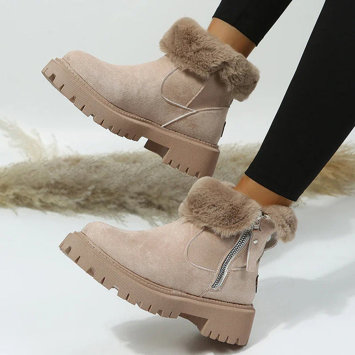 Beige suede ankle boots with thick rubber soles and faux fur trim worn with black leggings
